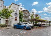 Thumbnail 29 of 33 - A blue car is parked in a parking lot in front of a building.