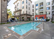 Thumbnail 3 of 46 - A swimming pool surrounded by buildings and chairs.