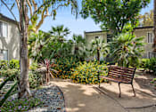 Thumbnail 9 of 15 - A bench sits in the middle of a garden at Twenty 2 Eleven Apartment Homes
