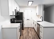 Thumbnail 13 of 28 - an empty kitchen with white cabinets and a black stove and refrigerator