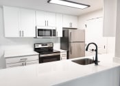 Thumbnail 15 of 28 - a white kitchen with stainless steel appliances and white counter tops