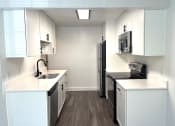 Thumbnail 2 of 18 - a kitchen with white cabinets and a sink and a refrigerator