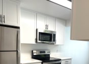 Thumbnail 4 of 18 - a kitchen with white cabinets and a stove and a microwave