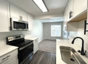 Thumbnail 1 of 18 - an empty kitchen with white cabinets and black appliances and a sink