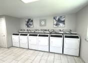 Thumbnail 16 of 18 - a row of white washers and dryers in a laundry room with a row