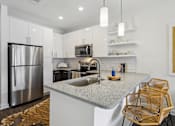 Thumbnail 10 of 33 - a kitchen with white cabinets and a granite counter top and a stainless steel refrigerator at Link Apartments® Broad Ave, Memphis, Tennessee