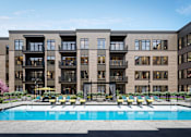 Thumbnail 21 of 33 - a swimming pool is in front of an apartment building at Link Apartments® Broad Ave, Memphis, TN