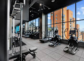 Thumbnail 38 of 39 - A gym with treadmills, weights, and a view of a cityscape at Link Apartments® QPN, Long Island City, New York