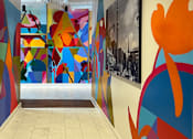 Thumbnail 23 of 32 - a hallway with a colorful mural on the wall and a staircase at Link Apartments® 4th Street, Winston-Salem, North Carolina