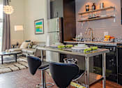 Thumbnail 12 of 37 - a kitchen with an island and two chairs in front of it at Link Apartments® Canvas, Georgia, 30312