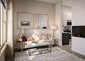 Thumbnail 9 of 25 - A living room with a white couch and a grey rug.