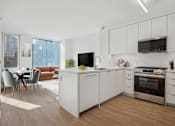 Thumbnail 3 of 34 - A modern kitchen with white cabinets and a wooden floor.
