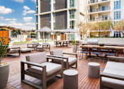 Thumbnail 5 of 28 - A patio with a table and chairs and a building in the background.