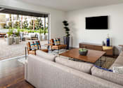 Thumbnail 3 of 28 - A living room with a grey couch, a wooden coffee table, and a flat screen TV mounted on the wall.