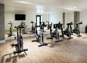 Thumbnail 11 of 28 - A room with a row of stationary bikes and a television mounted on the wall.