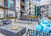 Thumbnail 4 of 18 - A patio with a fire pit and chairs.