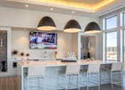 Thumbnail 10 of 18 - A modern kitchen with a bar area and a television mounted on the wall.