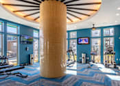 Thumbnail 14 of 18 - A gym with a blue carpet and a large yellow column in the middle.