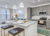 Thumbnail 17 of 18 - A modern kitchen with a white countertop and stainless steel appliances.