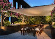 Thumbnail 17 of 34 - A patio with a table and chairs under a shade sail.