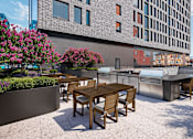 Thumbnail 14 of 34 - A patio with a table and chairs is in front of a building.