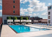 Thumbnail 11 of 34 - A pool with lounge chairs and a building in the background.