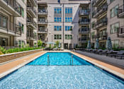 Thumbnail 16 of 32 - a swimming pool in the middle of an apartment building at Link Apartments® 4th Street, Winston-Salem, NC