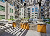 Thumbnail 17 of 32 - spacious clubhouse with grilling stations and apartments in the background at Link Apartments® 4th Street, Winston-Salem, 27101