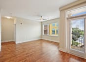 Thumbnail 17 of 28 - an empty living room with a large window and wood flooring at Link Apartments® Brookstown, Winston Salem, NC, 27101