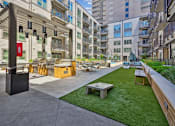 Thumbnail 12 of 32 - an outdoor lounge area with a picnic table and a grill in an apartment building at Link Apartments® 4th Street, Winston-Salem, North Carolina