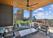 Thumbnail 13 of 32 - a balcony with a view of the city and a couch and a table at Link Apartments® 4th Street, North Carolina, 27101