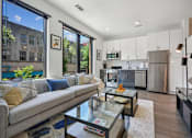 Thumbnail 10 of 32 - a living room with a couch and a coffee table in front of a kitchen at Link Apartments® 4th Street, Winston-Salem, 27101