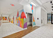 Thumbnail 27 of 32 - a hallway with a colorful mural on the wall and a door at Link Apartments® 4th Street, Winston-Salem