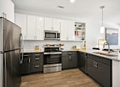 Thumbnail 21 of 32 - a modern kitchen with stainless steel appliances and white cabinets at Link Apartments® 4th Street, Winston-Salem, NC