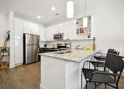 Thumbnail 4 of 32 - a kitchen with a granite counter top and a stainless steel refrigerator at Link Apartments® 4th Street, Winston-Salem, North Carolina