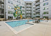 Thumbnail 5 of 22 - Courtyard pool with mural and lounge chairs at Link ® Lake Park Apartments, Smyrna, Georgia