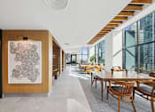 Thumbnail 30 of 39 - A long hallway with tables and chairs on either side at Link Apartments® QPN, Long Island City, New York