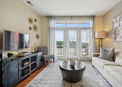 Thumbnail 6 of 28 - a living room with a couch and a tv and a balcony at Link Apartments® Brookstown, Winston Salem