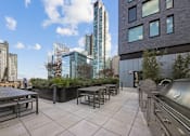 Thumbnail 32 of 39 - A rooftop patio with a table and chairs overlooking a city skyline at Link Apartments® QPN, Long Island City, New York