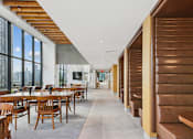 Thumbnail 36 of 39 - A long hallway with wooden benches on the right and tables on the left at Link Apartments® QPN, Long Island City, New York