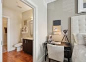 Thumbnail 12 of 28 - a bedroom with a desk and a bathroom with a toilet at Link Apartments® Brookstown, Winston Salem, NC, 27101