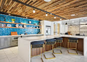 Thumbnail 18 of 32 - a kitchen with a counter and three chairs at Link Apartments® 4th Street, Winston-Salem