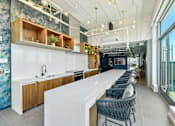 Thumbnail 21 of 32 - a long kitchen with a long white counter and chairs  at Link Apartments® H Street, Washington, 20002