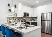 Thumbnail 13 of 25 - a kitchen with a island and a stainless steel refrigerator at Link Apartments® Mint Street, Charlotte, NC, 28203
