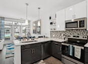 Thumbnail 14 of 25 - a kitchen with black and white appliances and a sink at Link Apartments® Mint Street, Charlotte, North Carolina