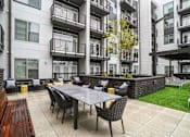 Thumbnail 9 of 25 - an outdoor patio with a table and chairs in front of an apartment building at Link Apartments® Mint Street, Charlotte, NC, 28203
