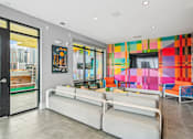 Thumbnail 5 of 25 - a living room with couches and a television and a colorful wall at Link Apartments® Mint Street, North Carolina
