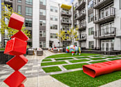 Thumbnail 20 of 25 - an apartment courtyard with a large red sculpture in front of an apartment building at Link Apartments® Mint Street, Charlotte, North Carolina