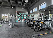 Thumbnail 25 of 31 - A gym with a row of treadmills and a motivational sign on the wall.