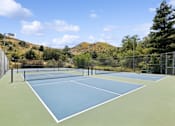 Thumbnail 19 of 23 - a tennis court with a fence and mountains in the background